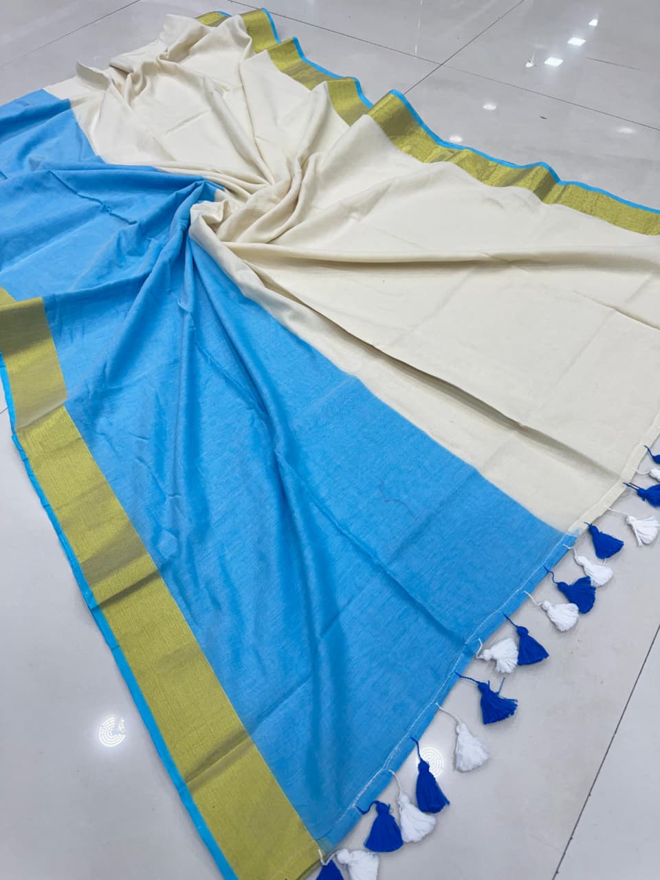 featuring sky-blue and cream panels with an olive-green border and blue-and-white tassel detailing on the pallu