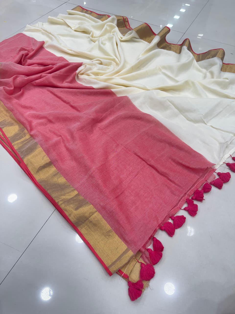 Rani Pink and cream panels with an olive-green border and blue-and-white tassel detailing on the pallu.